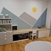 Kinderzimmer mit Wandbild von Bergen und Sonne.