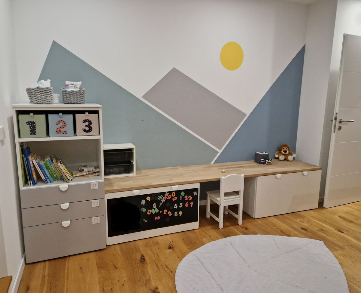 Kinderzimmer mit Wandbild von Bergen und Sonne.